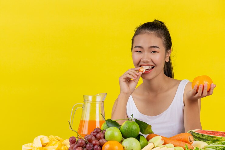 Kulit Kamu Kusam dan Ingin Kulit Glowing? 5 Tips Ini Bisa Kamu Lakukan Di Rumah 5 asian woman wearing white tank top eating orange table is full various fruits 1150 19088