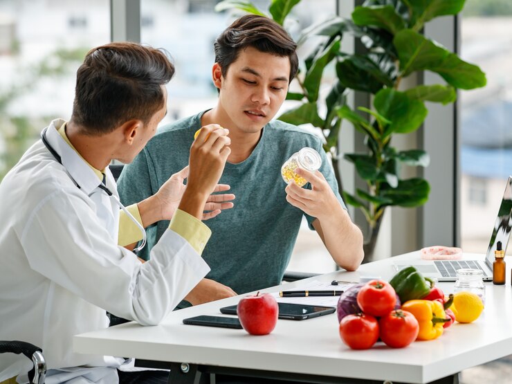 Musim Hujan Tiba! Ini 5 Tips Jitu agar Tidak Gampang Flu 2 male nutritionist showing discussing vitamin pills with asian man while sitting table with healthy food while working modern hospital 102814 3428
