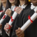 people graduating with diplomas close up