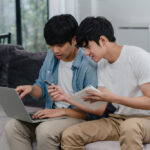 Alasan-Alasan Kenapa Generasi Milenial Harus Mulai Melakukan Investasi! 5 young asian gay couple working laptop modern home asia lgbtq men happy relax fun using computer analyzing their finances internet together while lying sofa living room house