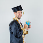 young man choosing destination school globe graduate uniform looking jolly