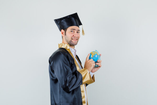 young man choosing destination school globe graduate uniform looking jolly