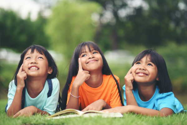 group children lying reading grass field