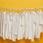 group white plain clothes hanging garment rack rail minimalistic concept apparel women isolated yellow background