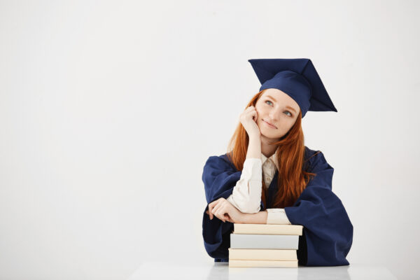 dreamy graduate woman smiling thinking sitting with books