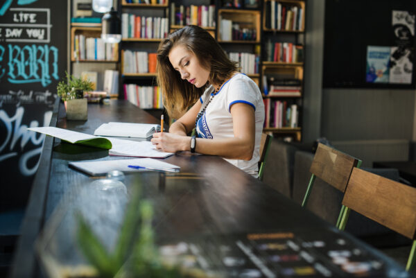 girl sitting table with notebooks writing