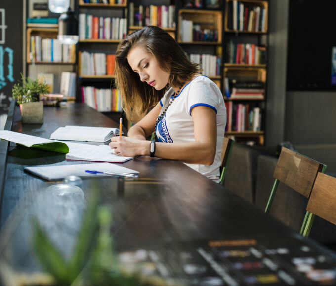 girl sitting table with notebooks writing