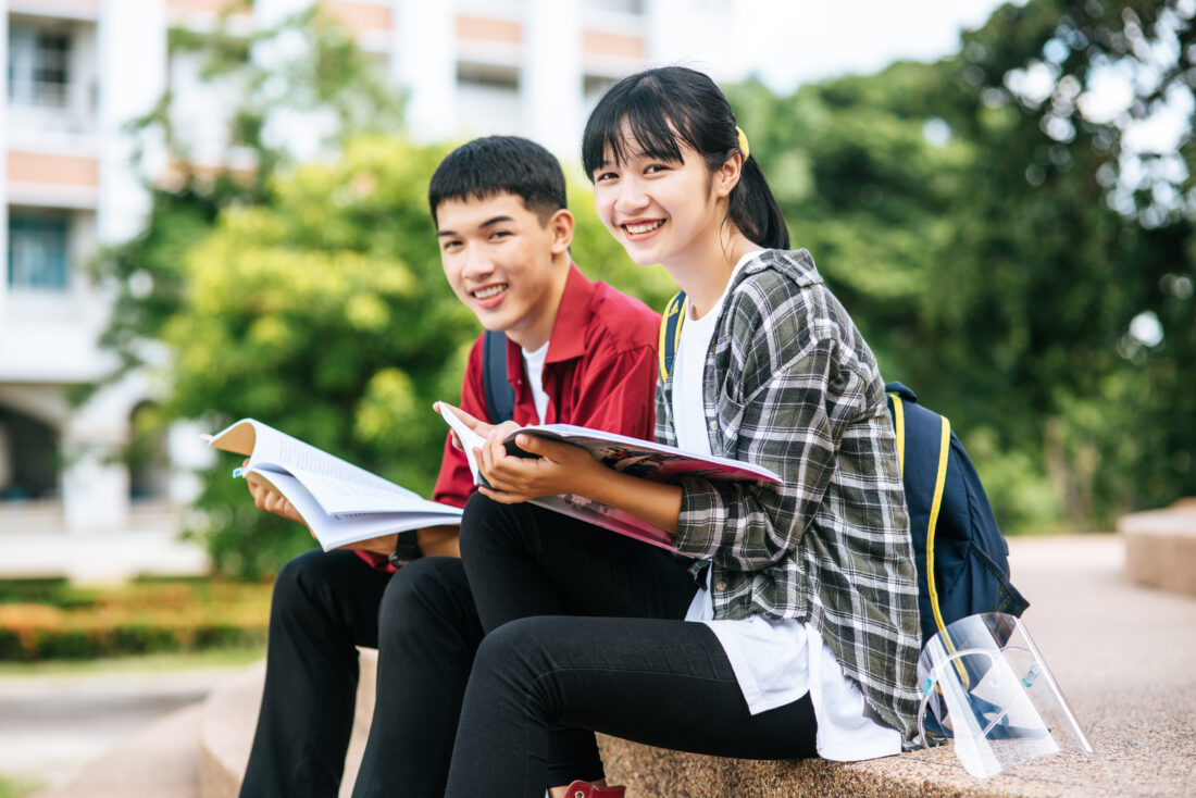 male female students sitting reading books stairs