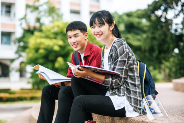 male female students sitting reading books stairs