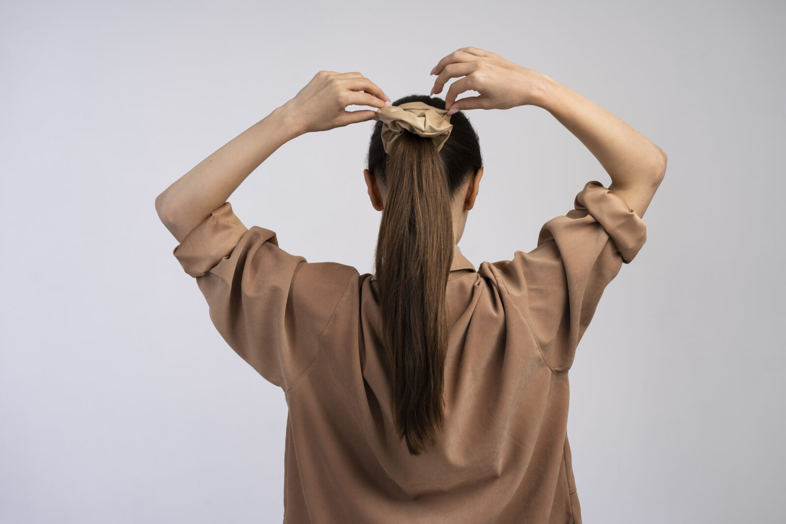 woman tying her hair back view