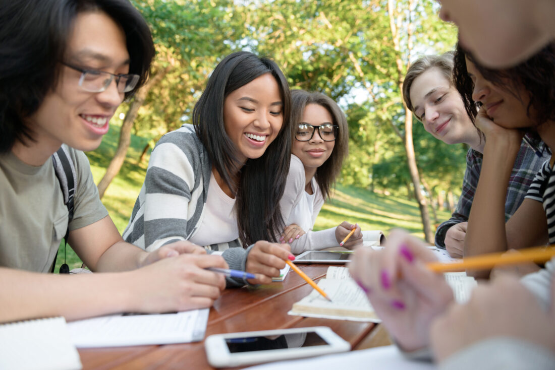 young students sitting studying outdoors while talking