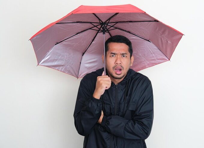adult asian man wearing jacket using umbrella with worried expression 524151 1965
