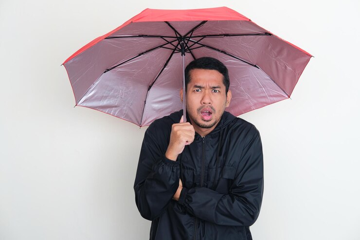 adult asian man wearing jacket using umbrella with worried expression 524151 1965