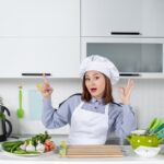 top view confident female chef fresh vegetables pointing up making eyeglasses gesture white kitchen 140725 114157