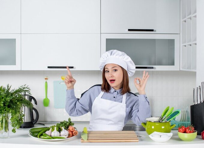 top view confident female chef fresh vegetables pointing up making eyeglasses gesture white kitchen 140725 114157