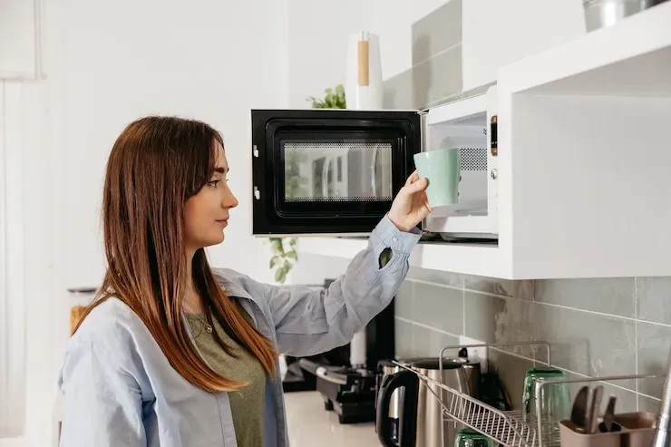 Bikin Tagihan Berkurang! 5 Tips Menghemat Listrik untuk Anak Kos 1 casual girl using microwave heat