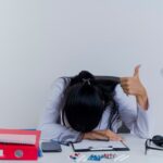 5 Tanda Kamu Butuh Pekerjaan Sampingan 3 tired young female doctor wearing medical robe stethoscope sitting desk with medical tools putting hand desk head hand showing thumb up isolated 141793 68849