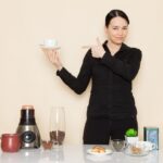 Tren Diet dengan Kopi: Apakah Aman Untuk Kesehatan? 3 female barista black shirt trousers front table with coffee ingredients equipment white wall 140725 11636