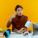Raih Prestasi Maksimal! 10 Tips Belajar Efektif yang Wajib Kamu Coba 5 thinking young student boy sitting desk with school tools holding book his thumb up yellow 141793 74786