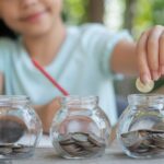 No Buy Challenge, 7 Cara Cerdas Menekan Pengeluaran dan Mengatur Keuangan dengan Bijak 5 cute asian little girl playing with coins making stacks money kid saving money into piggy bank into glass jar child counting his saved coins children learning about future concept 1150 45703