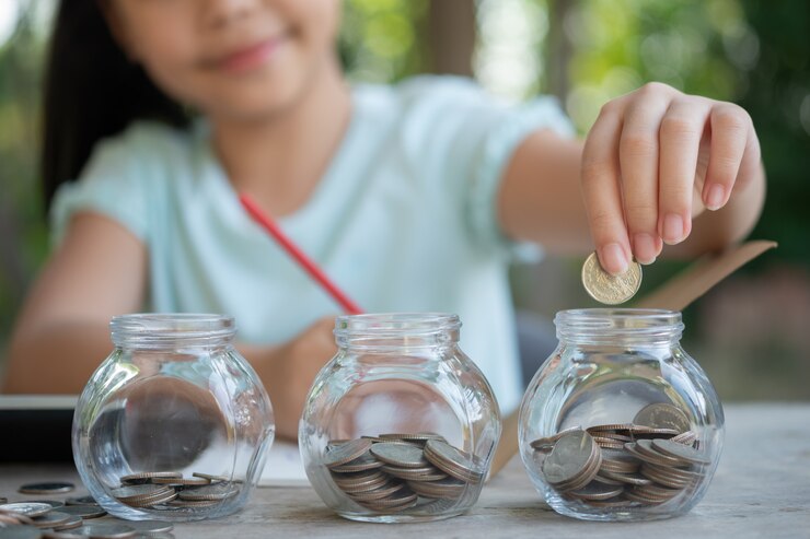 cute asian little girl playing with coins making stacks money kid saving money into piggy bank into glass jar child counting his saved coins children learning about future concept 1150 45703