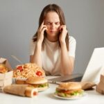 Lagi Stress Sering Lapar? Ini Dia Alasannya 5 indoor shot sick unhealthy woman sitting front laptop junk food having terrible headache being tire exhausted isolated gray background 176532 24927